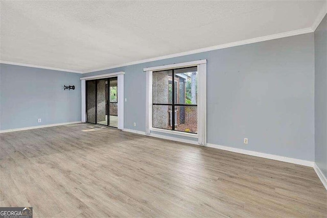 empty room with a textured ceiling, light hardwood / wood-style floors, and crown molding