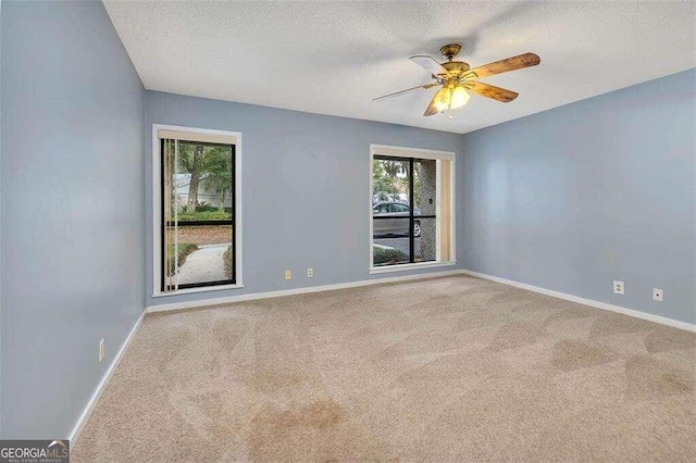 carpeted spare room with ceiling fan, a healthy amount of sunlight, and a textured ceiling