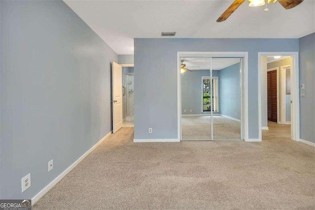 unfurnished bedroom featuring light carpet, a closet, and ceiling fan