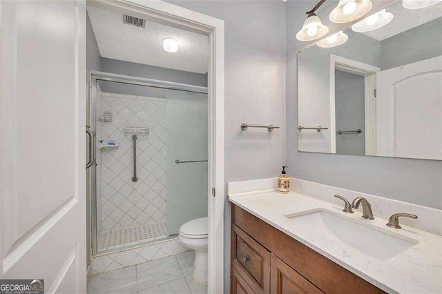 bathroom featuring vanity, tile patterned flooring, toilet, walk in shower, and a textured ceiling