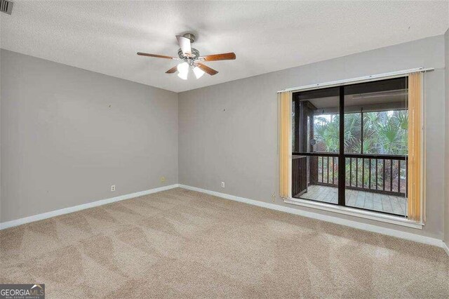 spare room featuring ceiling fan, a textured ceiling, and light carpet