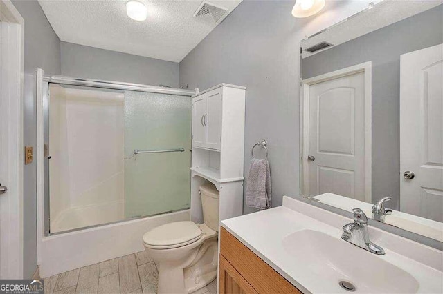 full bathroom featuring vanity, a textured ceiling, enclosed tub / shower combo, hardwood / wood-style floors, and toilet