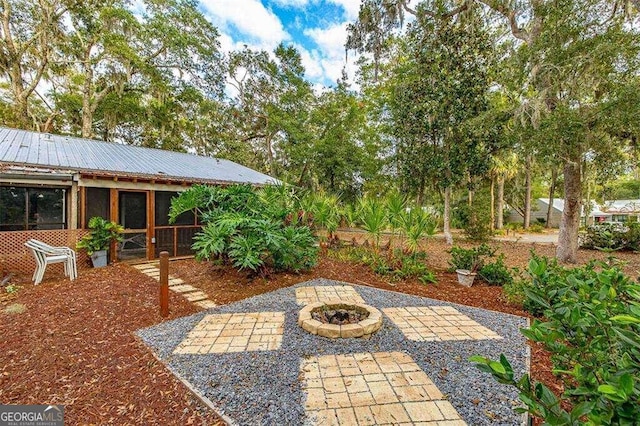 view of patio featuring a sunroom and an outdoor fire pit