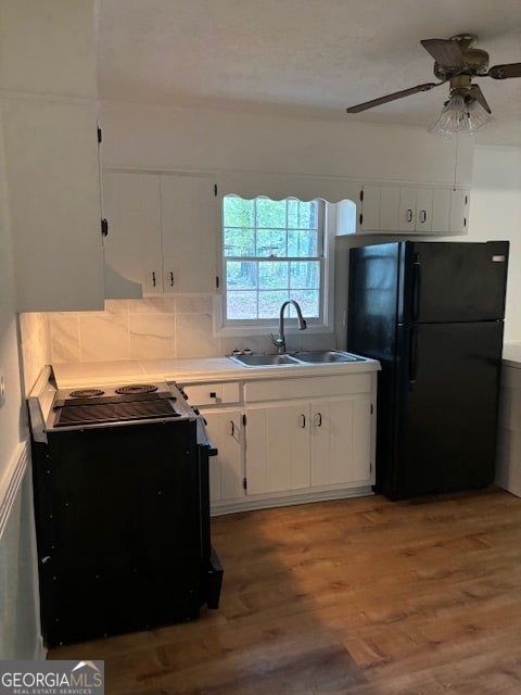 kitchen with hardwood / wood-style floors, sink, white cabinetry, and black appliances