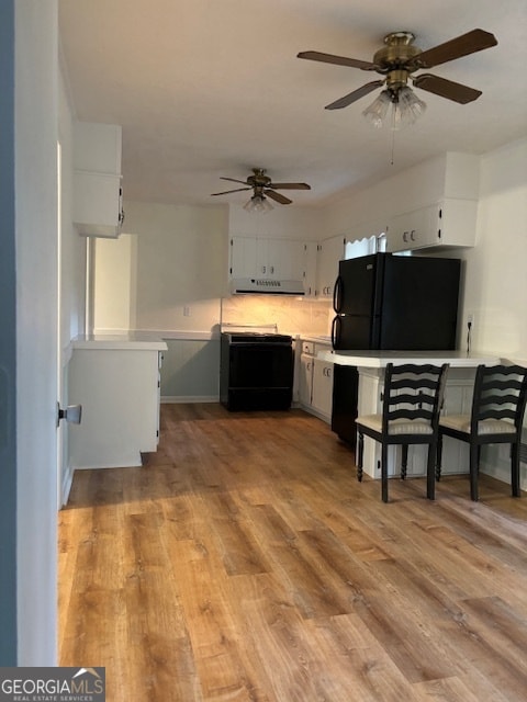 kitchen featuring decorative backsplash, kitchen peninsula, black appliances, light hardwood / wood-style flooring, and white cabinetry