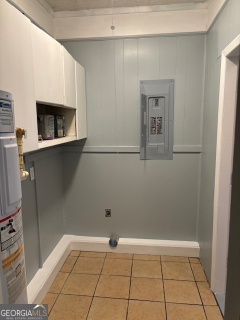 laundry room featuring cabinets, electric panel, water heater, hookup for an electric dryer, and light tile patterned flooring