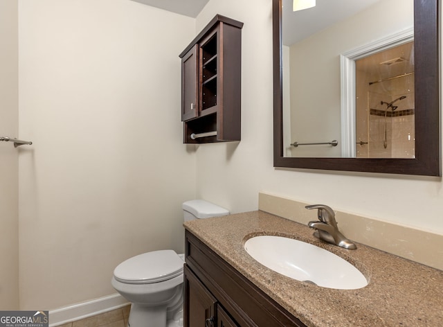 bathroom featuring tile patterned flooring, vanity, toilet, and a tile shower