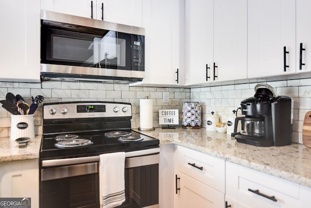 kitchen with decorative backsplash, light stone counters, white cabinetry, and appliances with stainless steel finishes