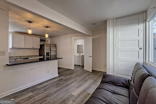 kitchen featuring white cabinets, stainless steel fridge, hardwood / wood-style flooring, and hanging light fixtures