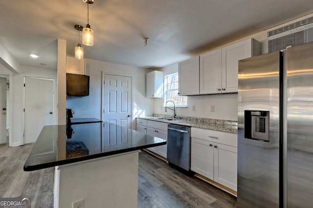 kitchen featuring appliances with stainless steel finishes, pendant lighting, white cabinetry, and a kitchen island