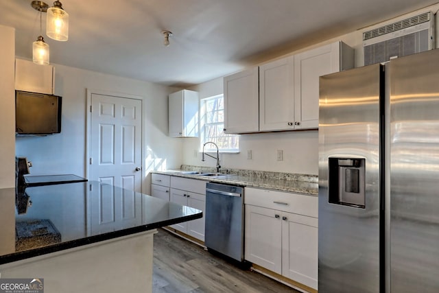 kitchen with hardwood / wood-style floors, dark stone counters, decorative light fixtures, white cabinets, and appliances with stainless steel finishes