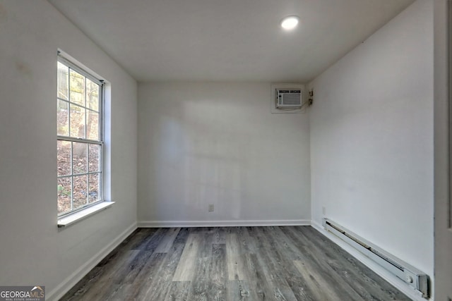 unfurnished room with a wall mounted air conditioner, dark hardwood / wood-style floors, and a baseboard heating unit