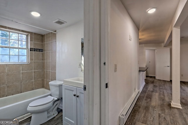 full bathroom featuring vanity, a baseboard radiator, hardwood / wood-style floors, toilet, and tiled shower / bath