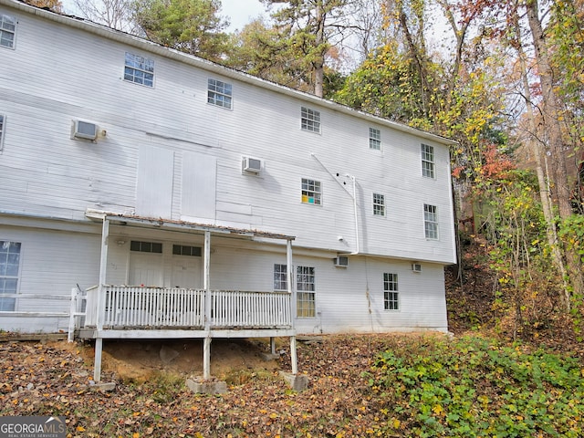 back of property with a wall mounted air conditioner and a deck