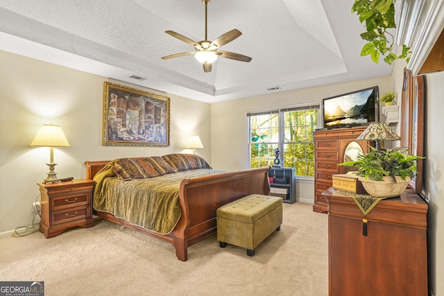 bedroom with ceiling fan, a raised ceiling, light carpet, and a textured ceiling