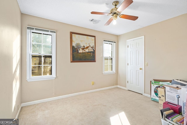 interior space featuring ceiling fan, light colored carpet, and a textured ceiling