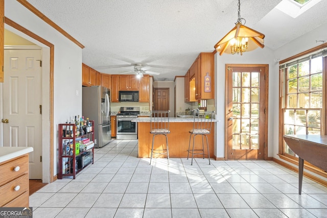 kitchen with light tile patterned flooring, stainless steel appliances, kitchen peninsula, and a kitchen bar