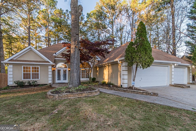 view of front of house featuring french doors, a front yard, and a garage