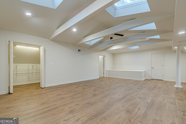 interior space with vaulted ceiling with skylight and light hardwood / wood-style floors