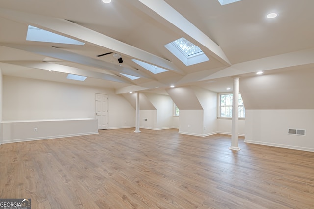 additional living space featuring light hardwood / wood-style flooring and vaulted ceiling with skylight