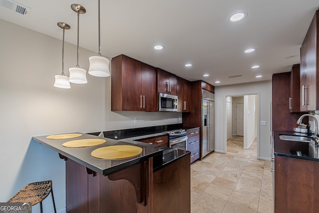 kitchen with sink, decorative light fixtures, a kitchen bar, kitchen peninsula, and stainless steel appliances