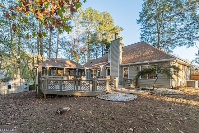 back of house featuring central AC, a shed, a sunroom, and a wooden deck