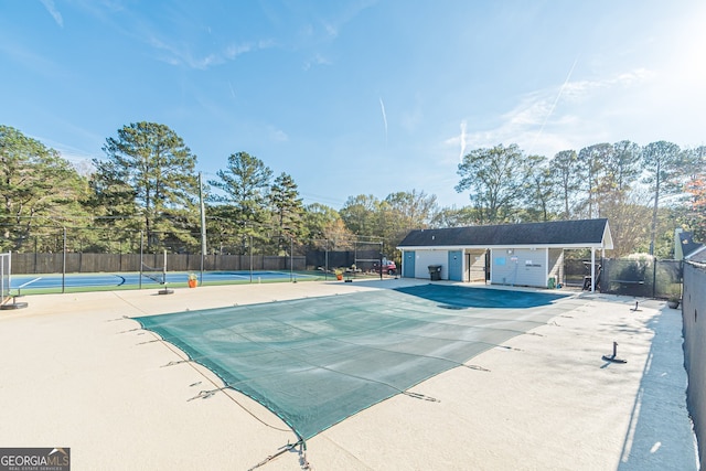 view of pool with a patio area, an outdoor structure, and tennis court