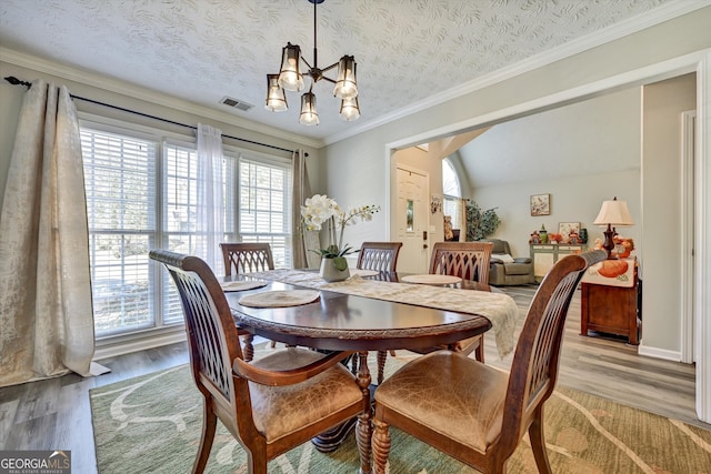 dining room featuring a chandelier, a textured ceiling, light hardwood / wood-style floors, and lofted ceiling