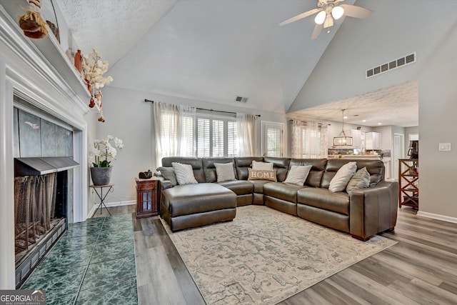 living room featuring wood-type flooring, a textured ceiling, high vaulted ceiling, and ceiling fan