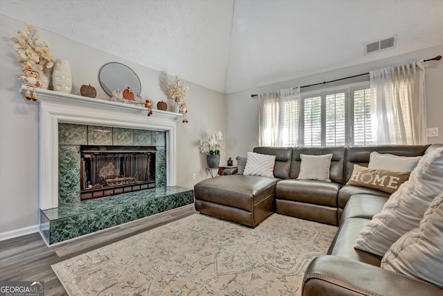 living room with a fireplace, hardwood / wood-style floors, a textured ceiling, and lofted ceiling