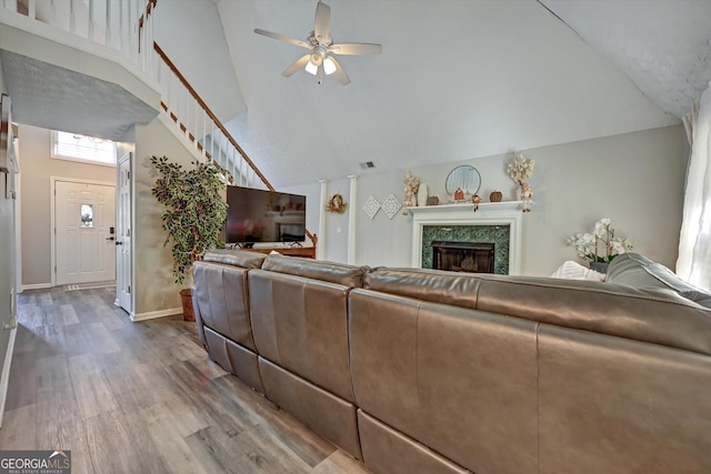 living room featuring a fireplace, wood-type flooring, high vaulted ceiling, and ceiling fan