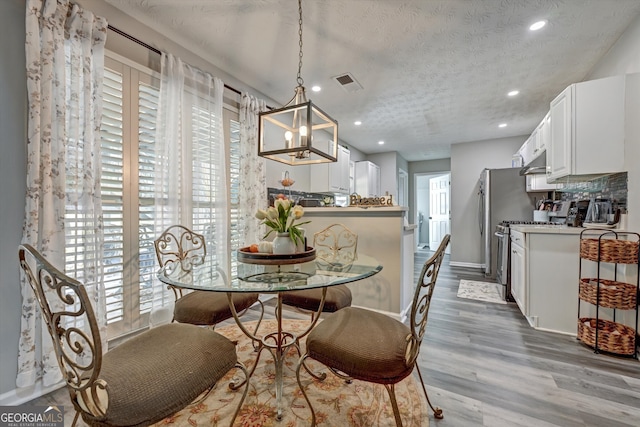 dining area with a notable chandelier, a textured ceiling, and hardwood / wood-style flooring