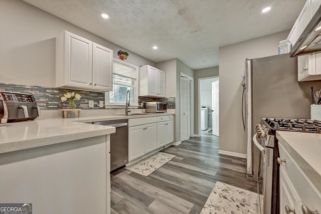 kitchen featuring white cabinets, stainless steel appliances, a textured ceiling, and light hardwood / wood-style floors