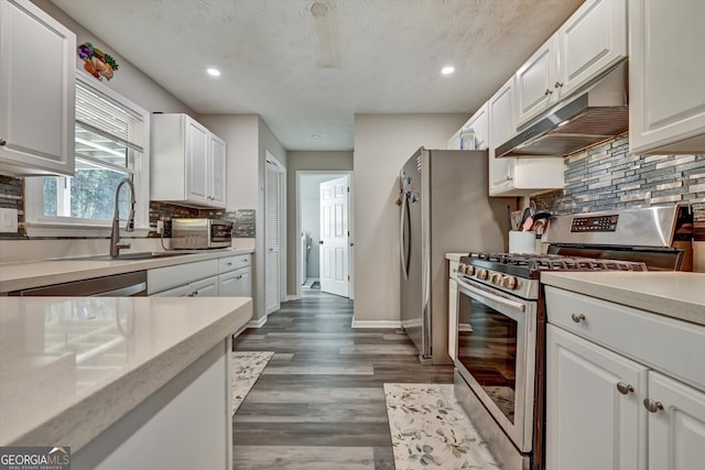 kitchen featuring backsplash, sink, appliances with stainless steel finishes, dark hardwood / wood-style flooring, and white cabinetry