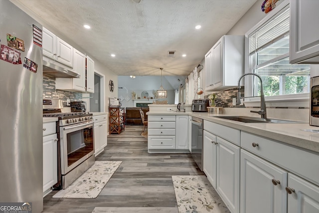 kitchen featuring pendant lighting, hardwood / wood-style floors, a textured ceiling, white cabinetry, and stainless steel appliances