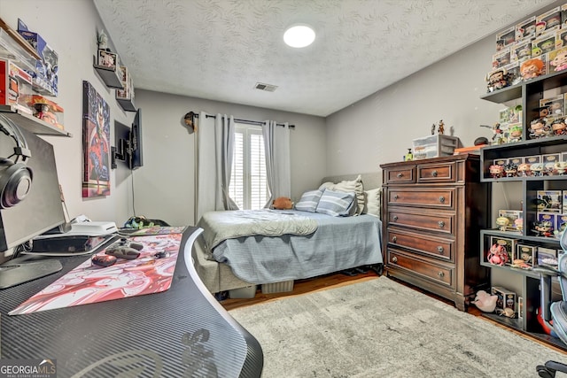 bedroom with wood-type flooring and a textured ceiling