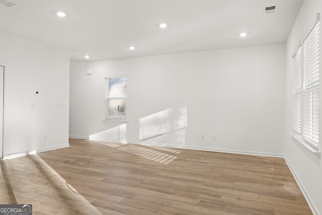 kitchen featuring stainless steel appliances, white cabinetry, light hardwood / wood-style floors, and a center island with sink