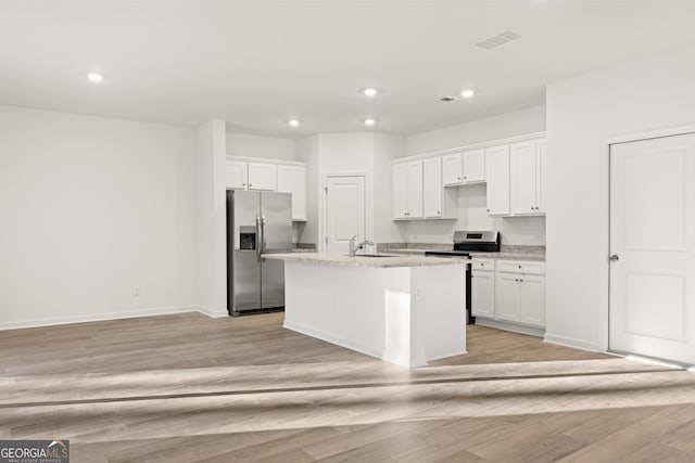 kitchen featuring light hardwood / wood-style flooring, white cabinets, stainless steel appliances, and a center island with sink