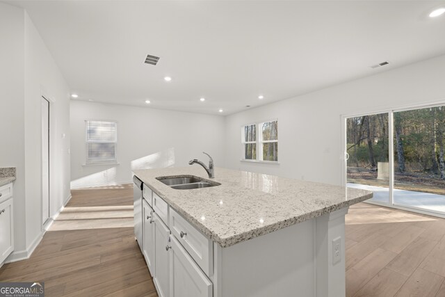 kitchen with white cabinetry, an island with sink, light hardwood / wood-style floors, and appliances with stainless steel finishes