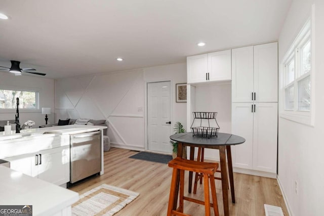 kitchen featuring white cabinetry, dishwasher, ceiling fan, and light wood-type flooring