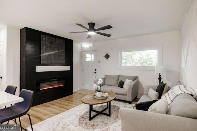 living room with ceiling fan, light wood-type flooring, and a fireplace