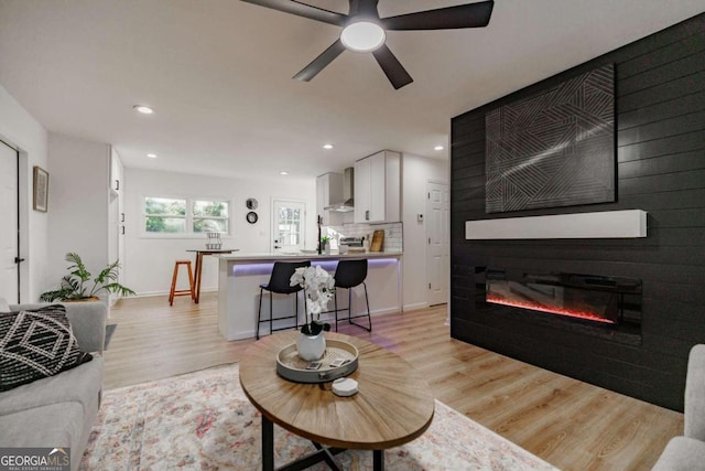 living room featuring a large fireplace, ceiling fan, and light hardwood / wood-style flooring