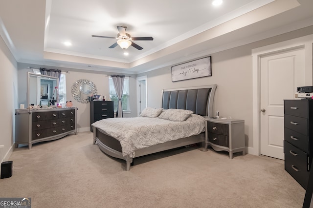 bedroom featuring a tray ceiling, ceiling fan, crown molding, and light carpet