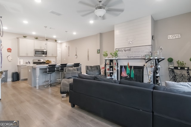 living room with light hardwood / wood-style flooring and ceiling fan