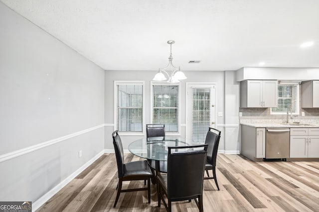 dining space with a notable chandelier, light hardwood / wood-style floors, and sink