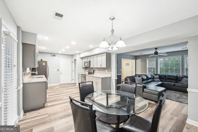 dining area with ceiling fan with notable chandelier and light wood-type flooring