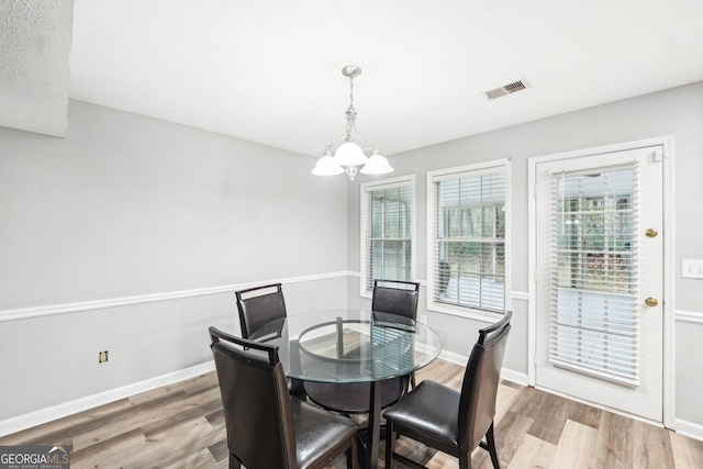 dining room with light hardwood / wood-style flooring and an inviting chandelier