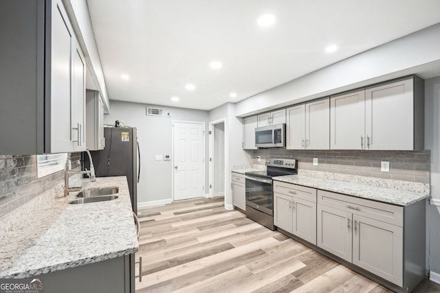 kitchen featuring sink, stainless steel appliances, gray cabinetry, and light hardwood / wood-style floors