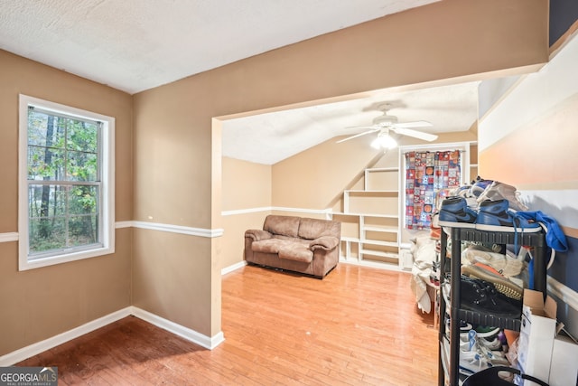 living area with a textured ceiling, light wood-type flooring, and ceiling fan