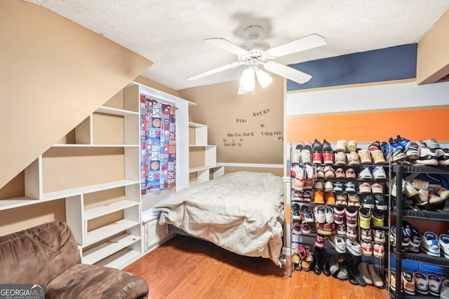 bedroom with a textured ceiling, hardwood / wood-style flooring, and ceiling fan